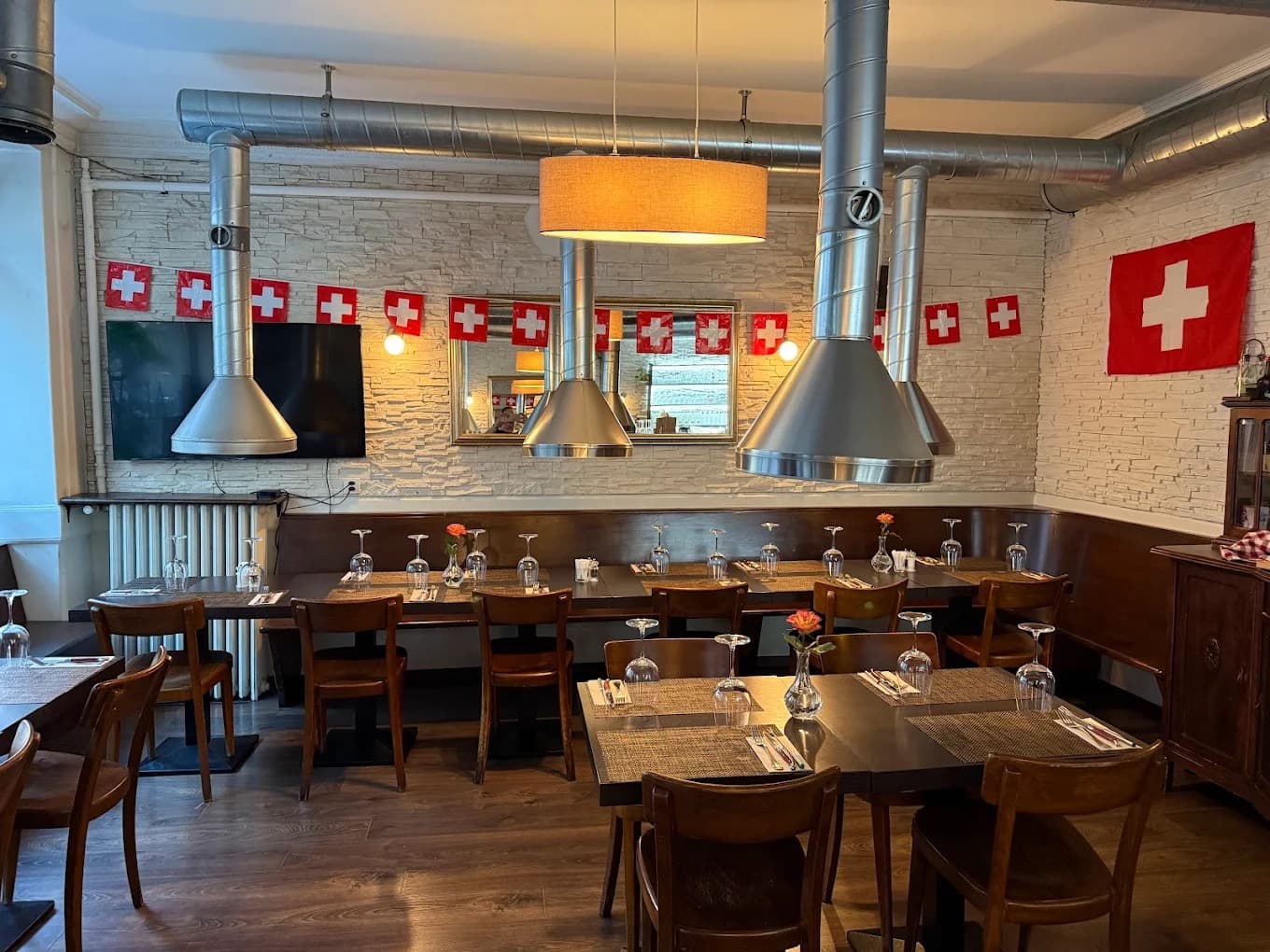 Salle chaleureuse du Restaurant Acacia à Genève, pierre claire, tables en bois et drapeaux suisses