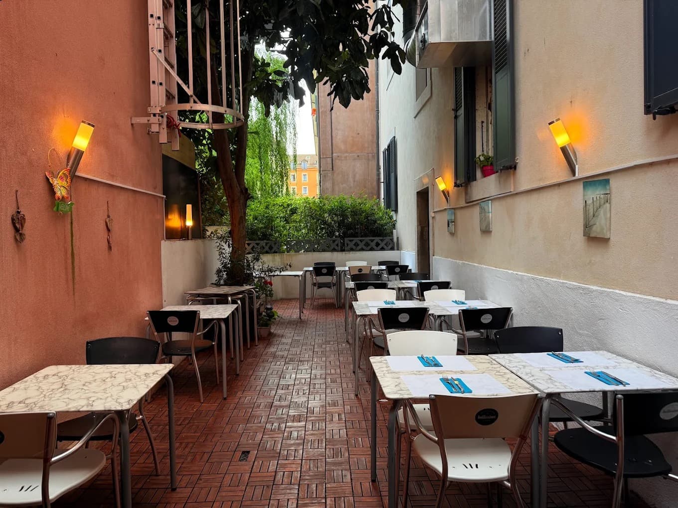 Terrasse extérieure du Restaurant Acacia, dans une cour pavée bordée d'un arbre